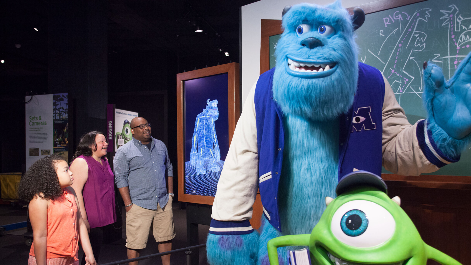 Family looking at Monsters U exhibit within Pixar