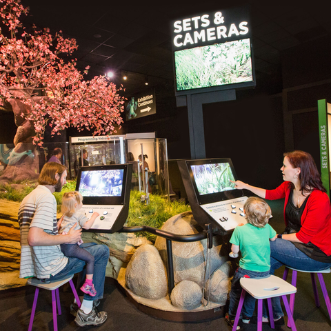 Family of four interacting with sets & cameras in Pixar exhibit