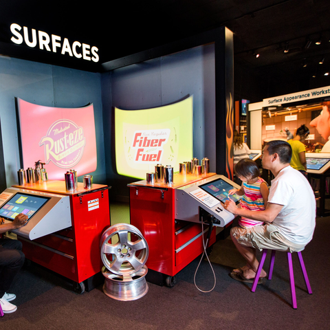 Two visitors interacting with "surfaces" on interactive display