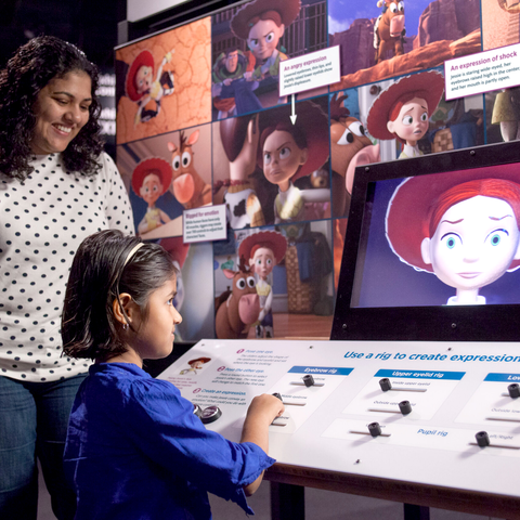Young girl and mother interacting with Toy Story "rig" to see expressions