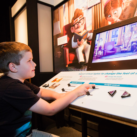 Boy interacting with virtual lighting exhibit with the movie UP