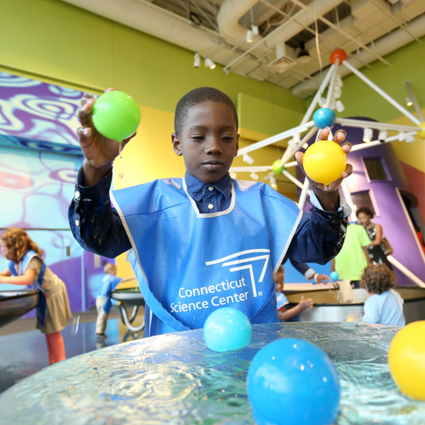 Young boy playing with balls in the water