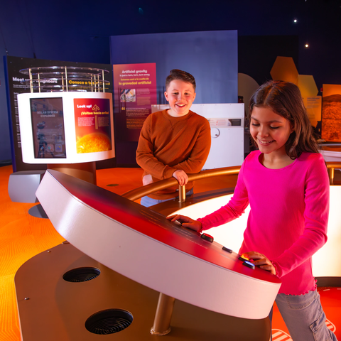A girl and boy looking at the gravity jump exhibit in Exploring Space