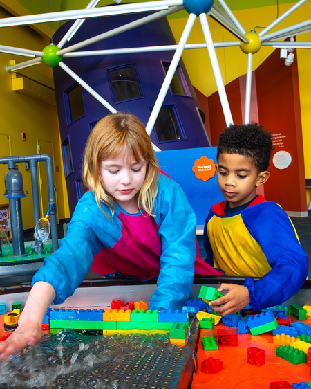 Two children playing with Legos at a table