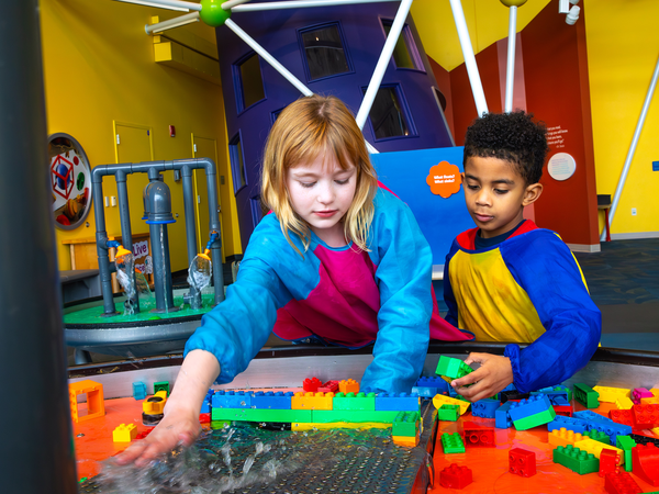 Two children playing with Legos at a table